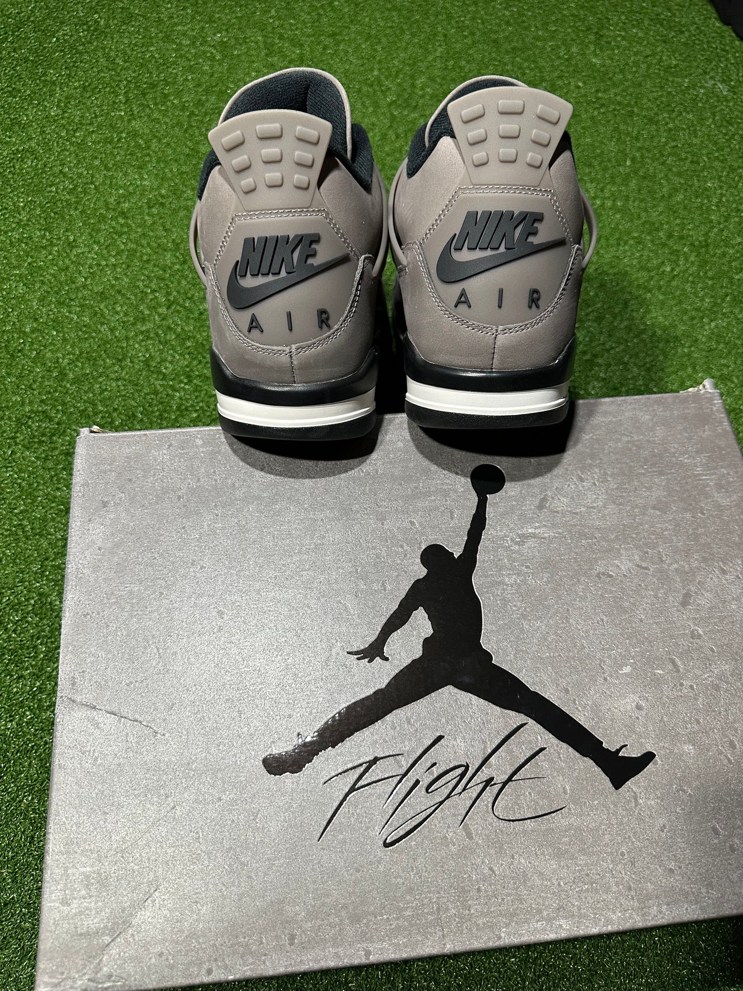 Gray Nike Air sneakers on a silver box with a silhouette of a person and the word 'Flight'.Air Jordan 4 Retro Cave Stone sneaker outsole traction pattern