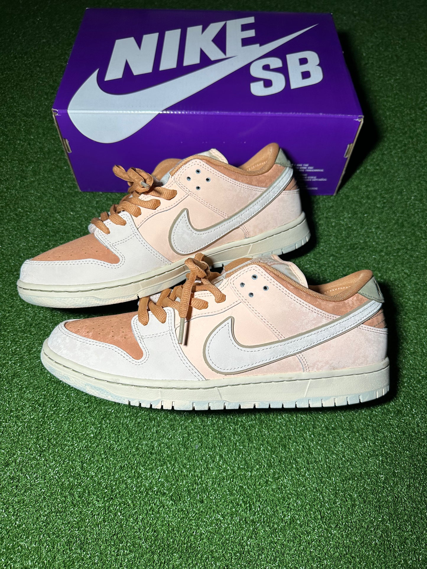 Pair of beige and brown Nike SB sneakers with a purple box in the background.