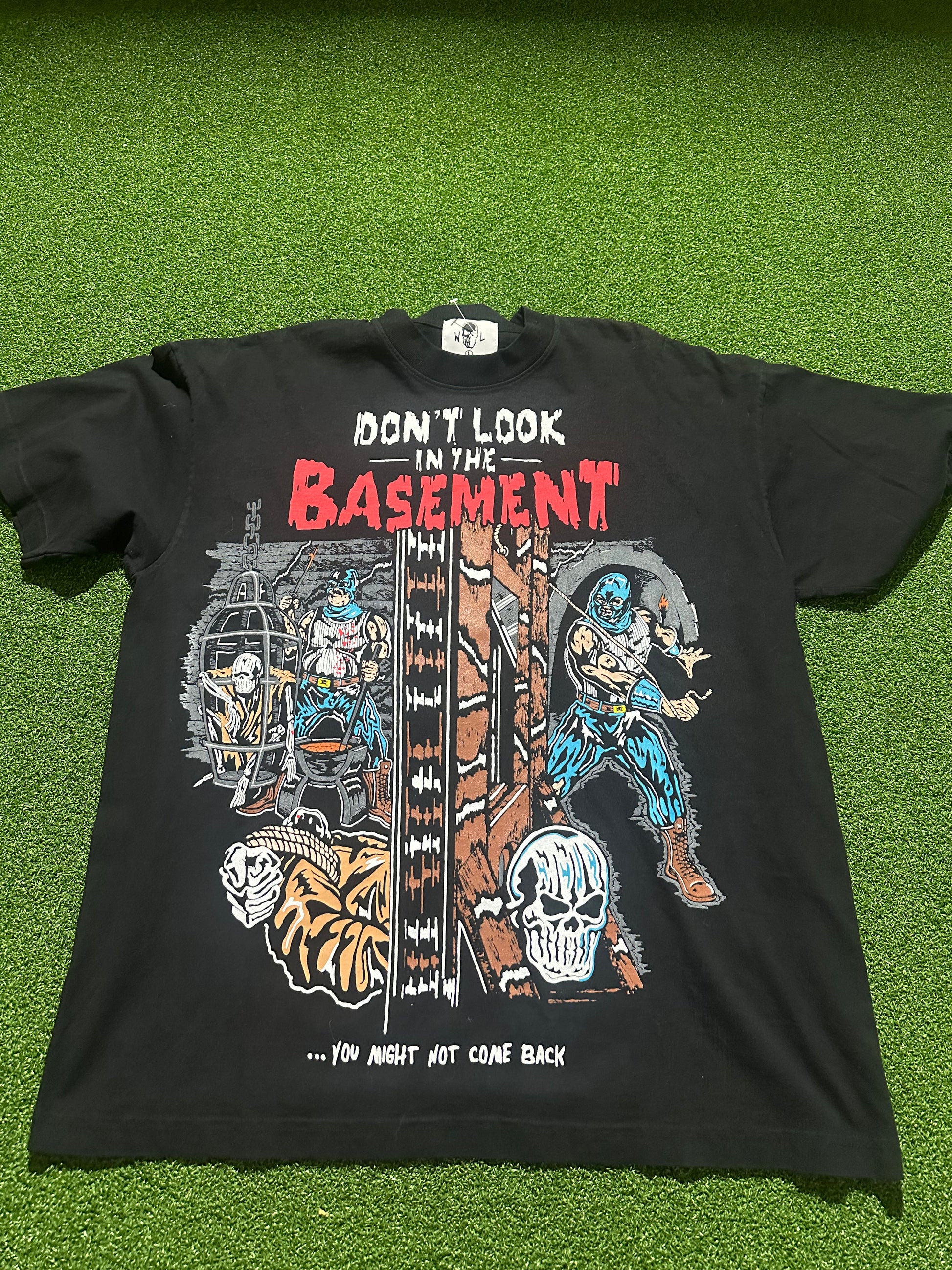 Black t-shirt with graphic design and text 'Don't Look in the Basement' on a green grass background