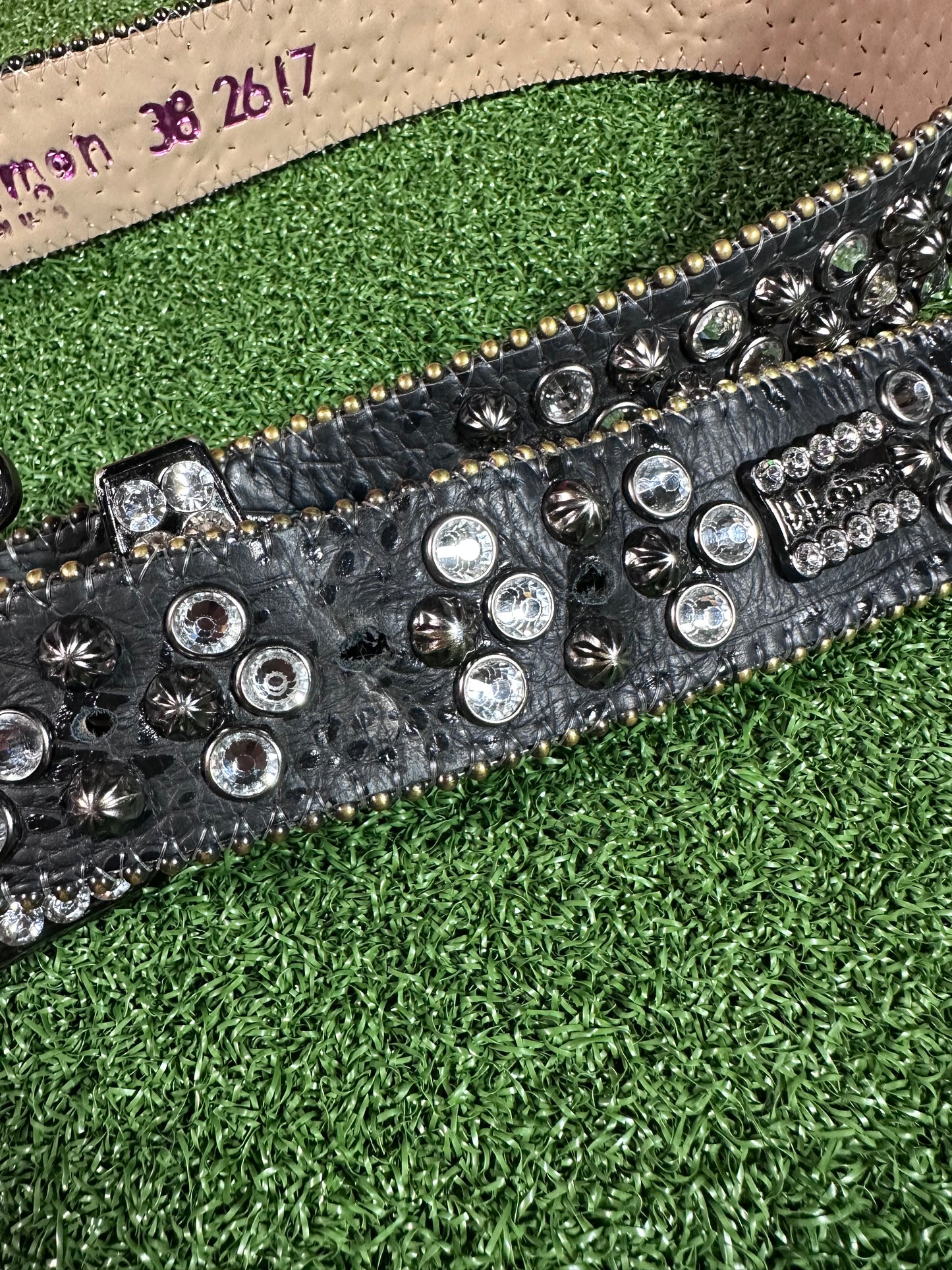 Close-up of a studded belt on a green grass background