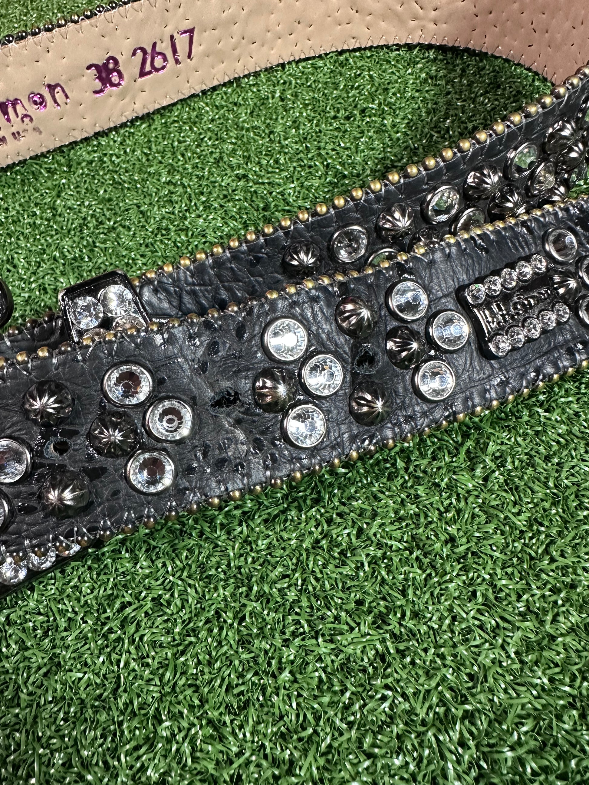 Close-up of a studded belt on a green grass background