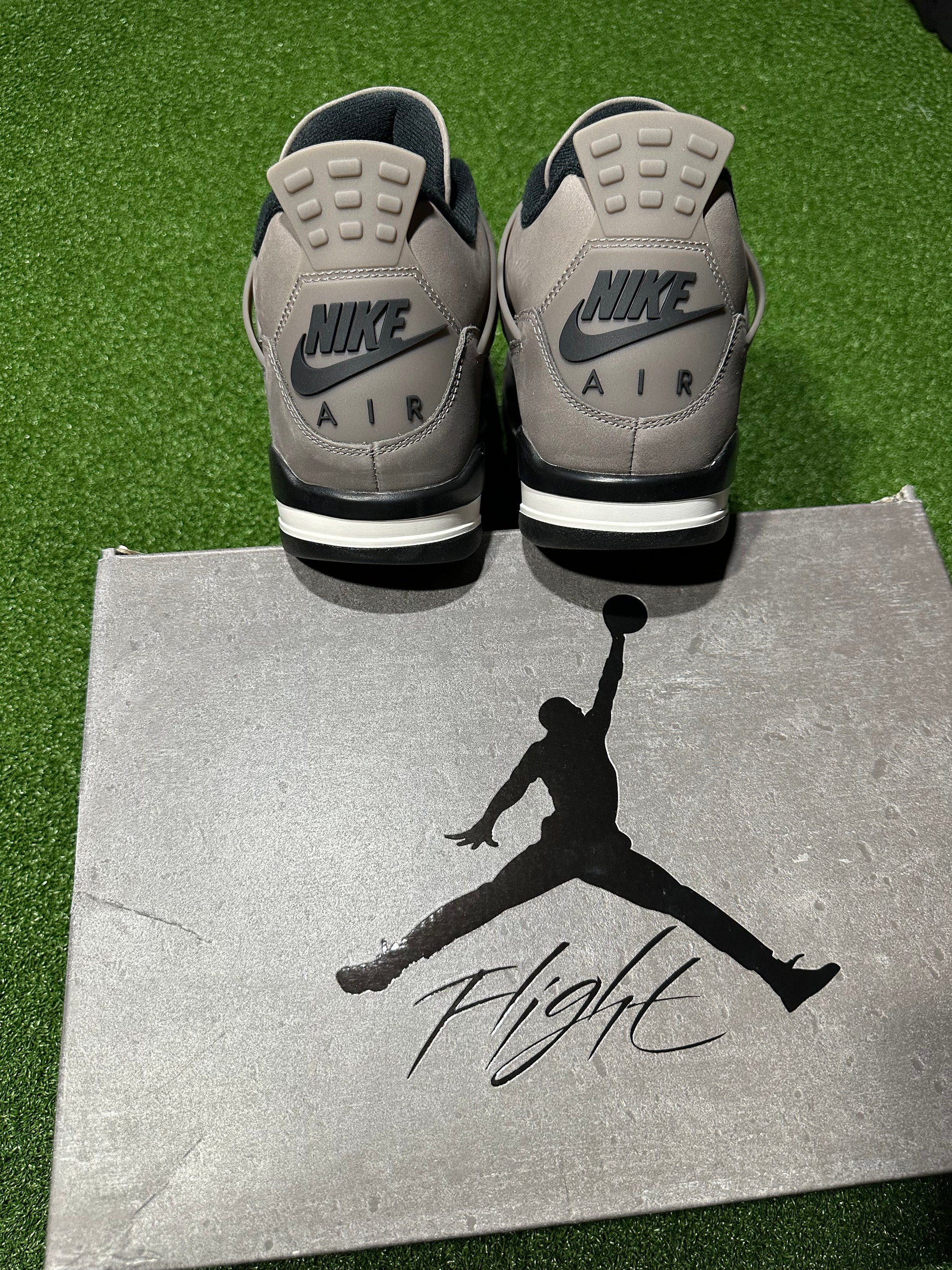 Gray Nike Air sneakers on a silver box with a silhouette of a person and the word 'Flight'.Air Jordan 4 Retro Cave Stone sneaker outsole traction pattern