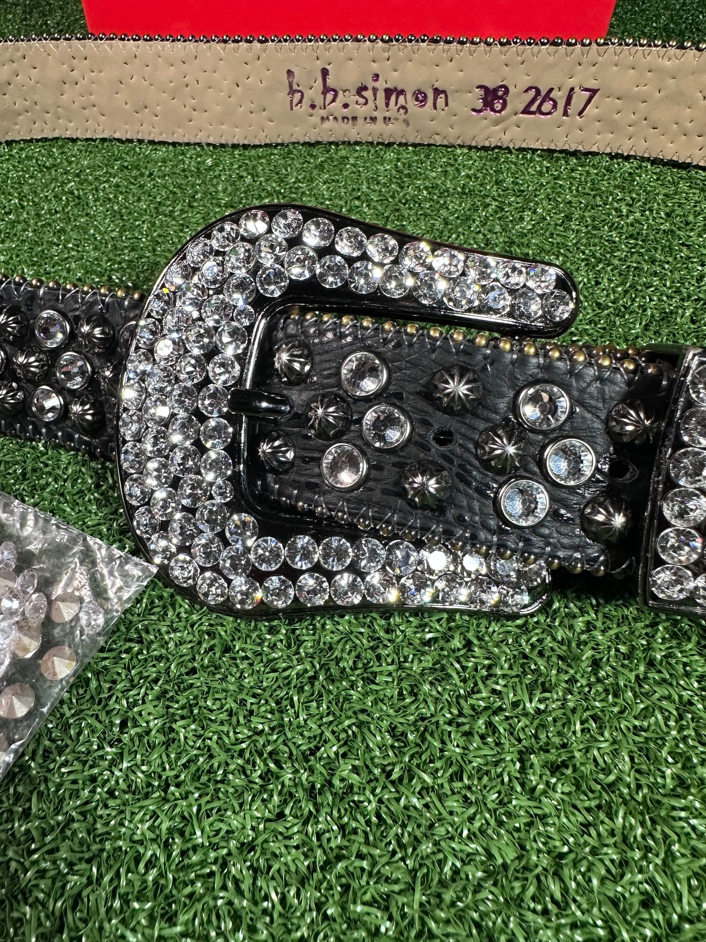 Decorative belt buckle with crystals on a green grass background